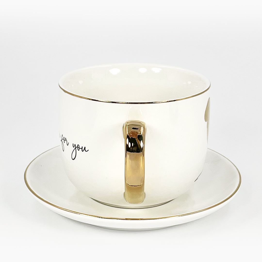 A white ceramic cup and saucer with gold handle and rim.